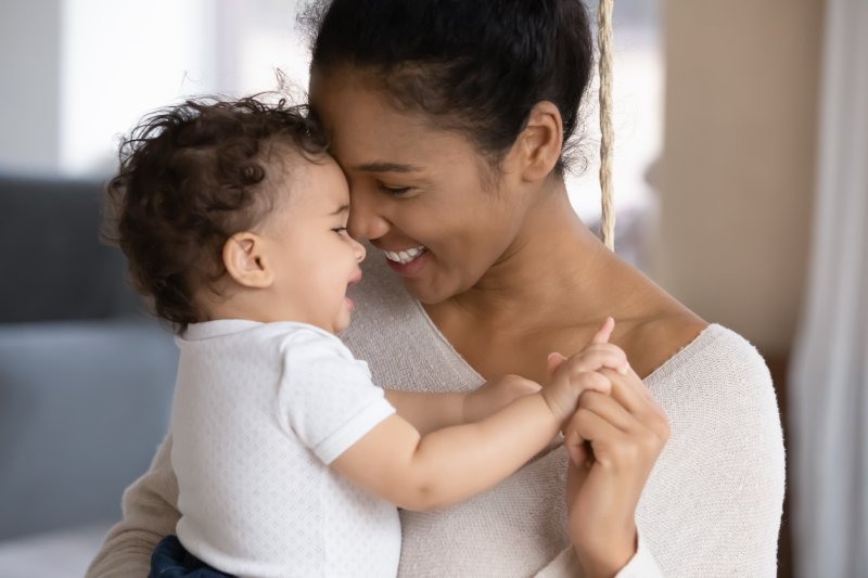 a mother holding her baby and both of them smiling